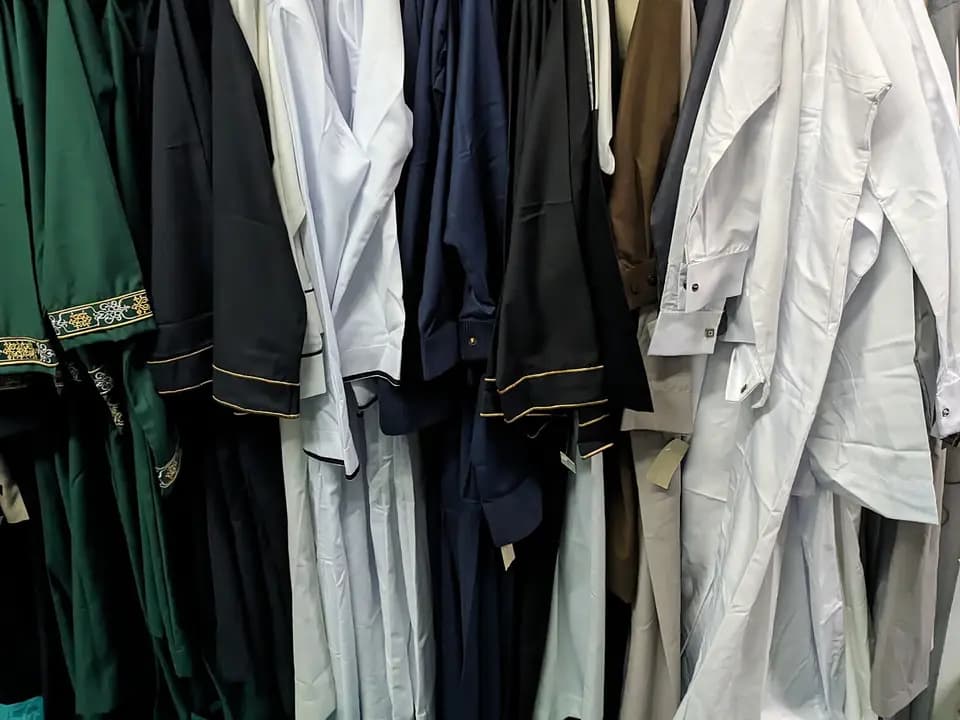 Deretan gamis dan jubah tergantung di toko busana muslim