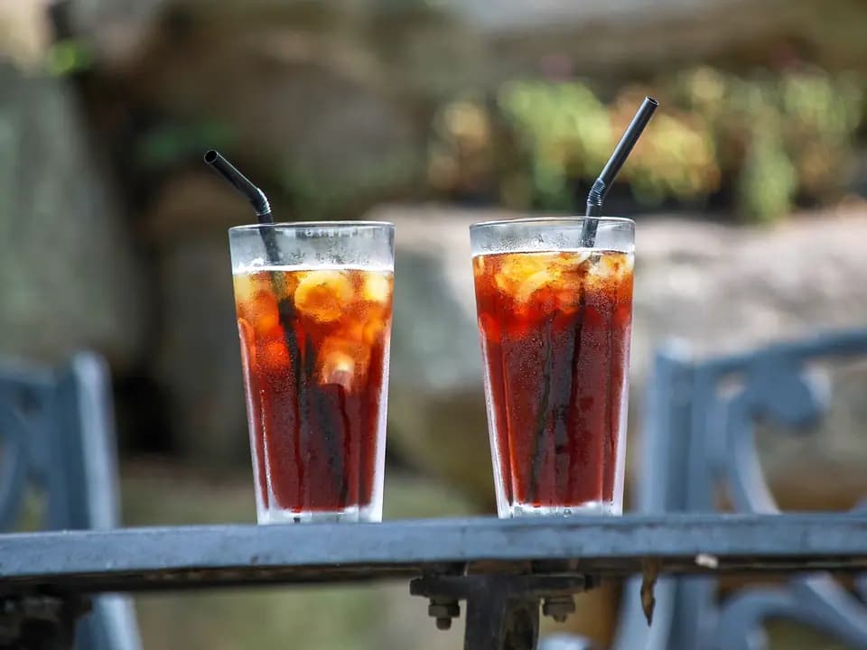 Dua gelas minuman dingin berisi es dengan sedotan